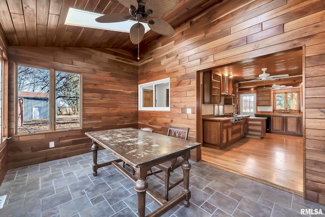 unfurnished dining area featuring wood ceiling, ceiling fan, vaulted ceiling, and wood walls