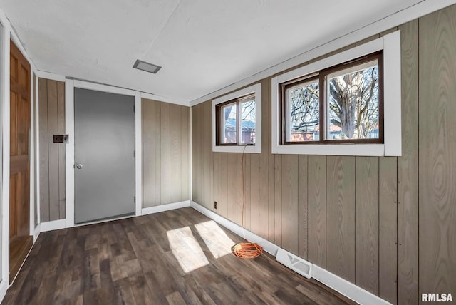 unfurnished bedroom with dark hardwood / wood-style flooring and wood walls