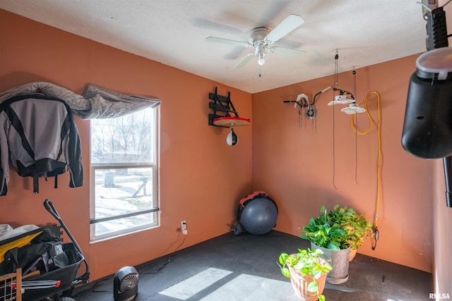 exercise room with ceiling fan and a textured ceiling