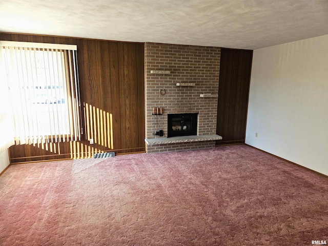 unfurnished living room featuring carpet flooring, a fireplace, a textured ceiling, and wood walls