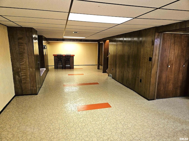 basement with a paneled ceiling and wooden walls