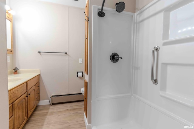 bathroom featuring a baseboard heating unit, vanity, wood-type flooring, a shower, and toilet