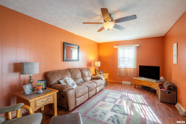 living room with visible vents, wood finished floors, and a ceiling fan