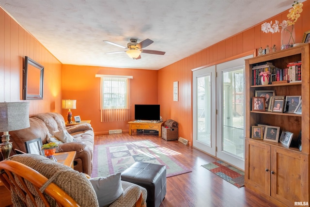 living room featuring ceiling fan, wood finished floors, and visible vents