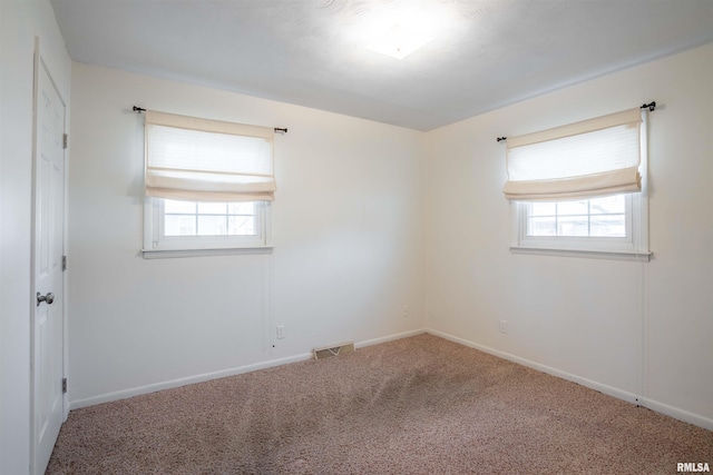 carpeted spare room with visible vents and baseboards