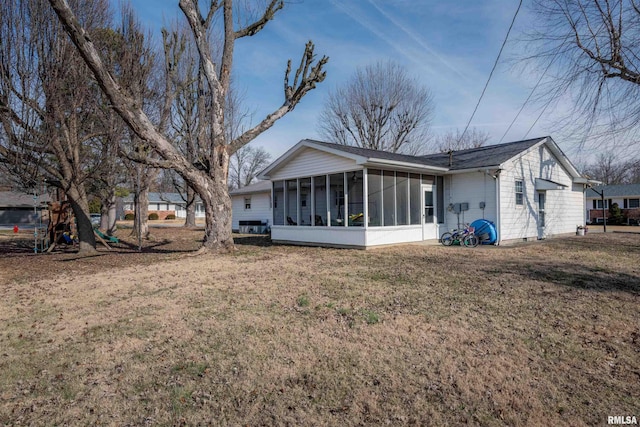 rear view of property with a yard and a sunroom