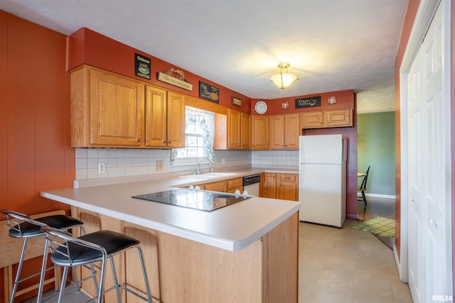 kitchen with a sink, light countertops, a kitchen bar, white appliances, and a peninsula