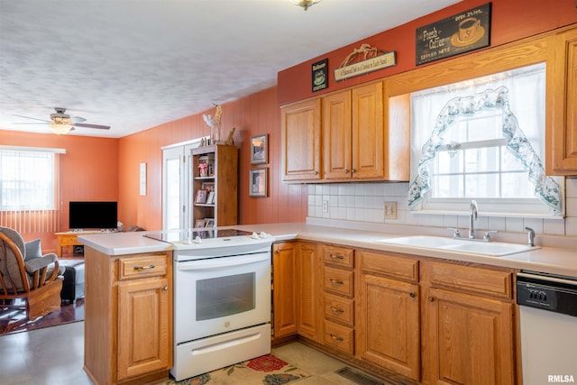 kitchen featuring a sink, a peninsula, a wealth of natural light, and white appliances