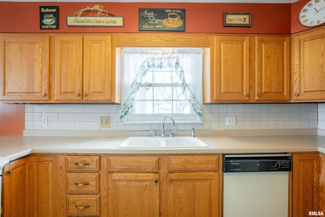kitchen with tasteful backsplash, light countertops, dishwasher, and a sink