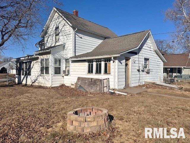 view of side of home with an outdoor fire pit and a yard