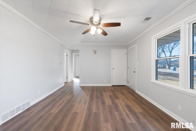 empty room with dark wood-style flooring, visible vents, crown molding, and baseboards