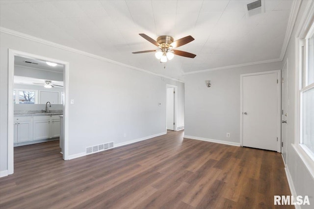 empty room featuring visible vents, dark wood-style flooring, a sink, and ornamental molding