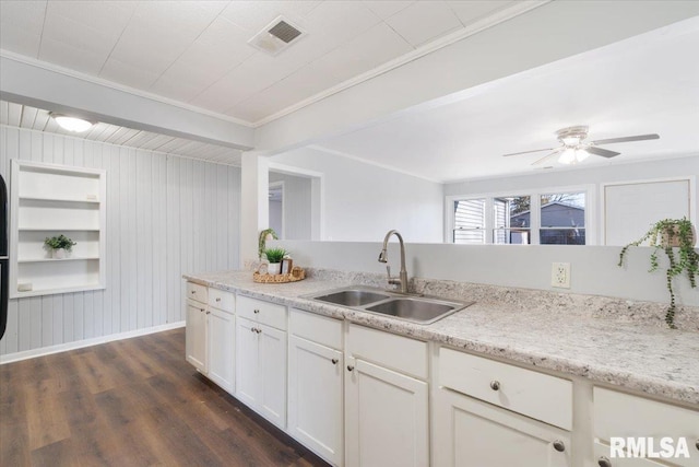 kitchen with a sink, visible vents, white cabinetry, dark wood finished floors, and crown molding