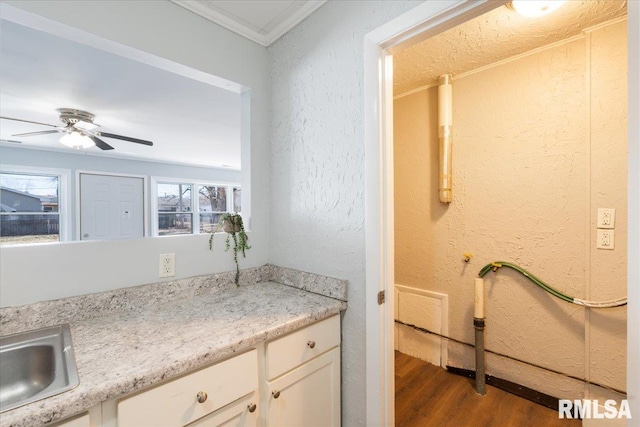 interior space with ceiling fan, a textured wall, wood finished floors, and crown molding