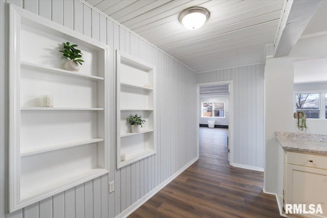 hall with a healthy amount of sunlight, baseboards, built in features, and dark wood-style flooring