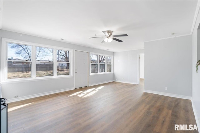 empty room featuring wood finished floors, a ceiling fan, and baseboards