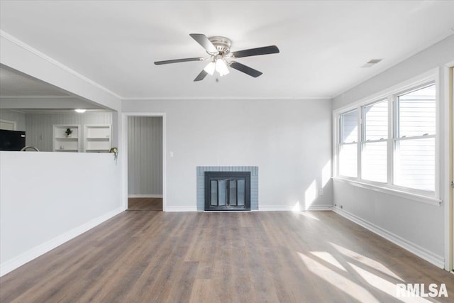 unfurnished living room featuring wood finished floors, a ceiling fan, baseboards, ornamental molding, and a brick fireplace