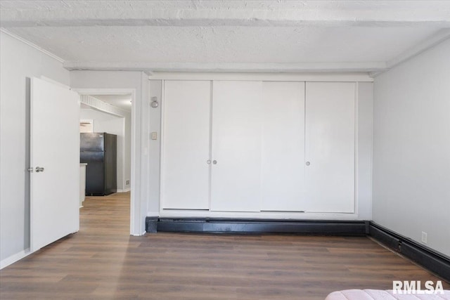 interior space with a textured ceiling, a closet, wood finished floors, and freestanding refrigerator