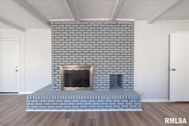 unfurnished living room with a brick fireplace, a textured ceiling, beam ceiling, and wood finished floors