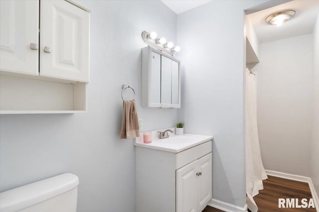 full bath featuring toilet, baseboards, wood finished floors, and vanity