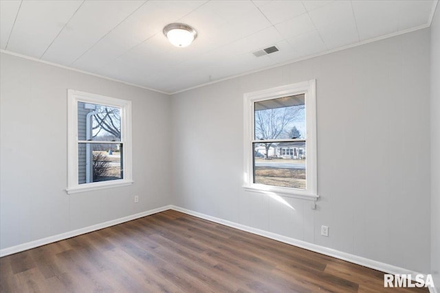 unfurnished room with visible vents, ornamental molding, dark wood finished floors, and baseboards