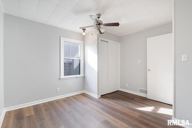 unfurnished bedroom featuring a closet, visible vents, a ceiling fan, wood finished floors, and baseboards