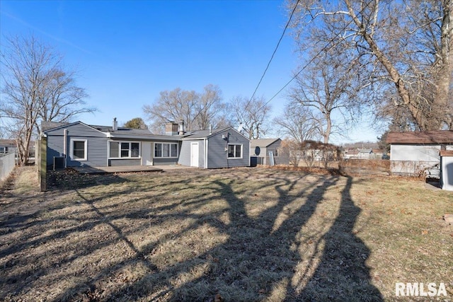 back of house with a lawn, a chimney, and fence