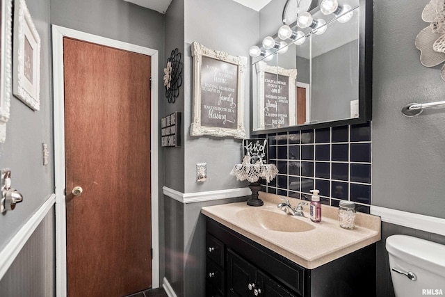 bathroom with vanity, toilet, and decorative backsplash