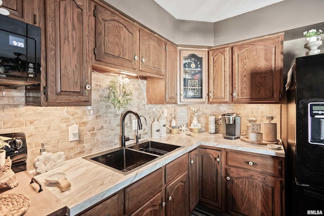 kitchen featuring sink, decorative backsplash, and black appliances