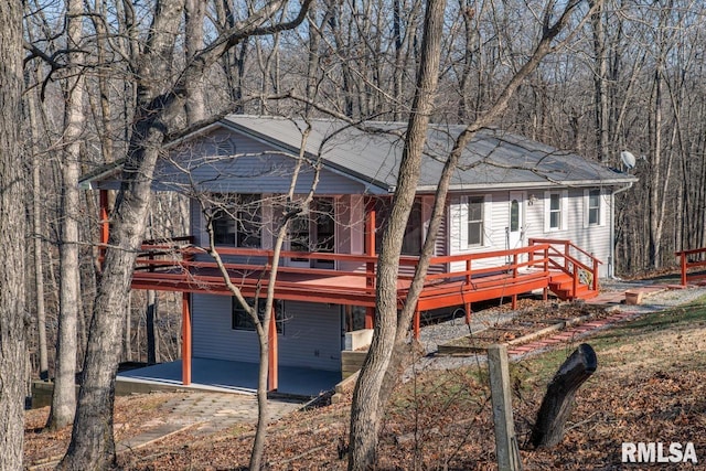 rear view of house with a wooden deck and a patio area