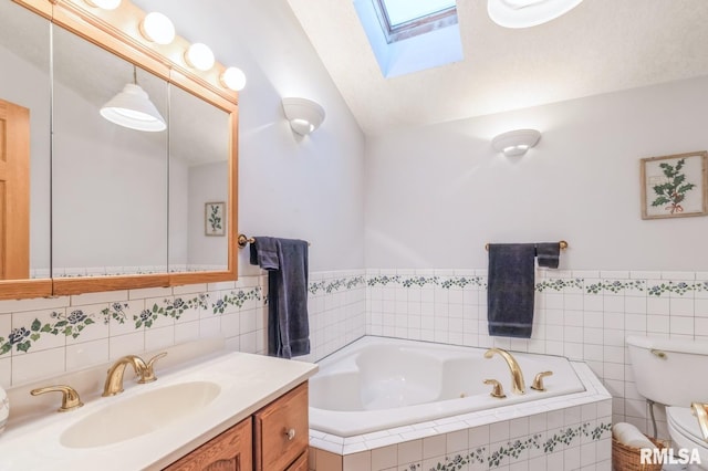 bathroom featuring toilet, vanity, vaulted ceiling with skylight, and a relaxing tiled tub