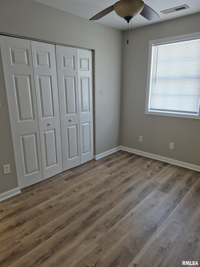 unfurnished bedroom with dark wood-type flooring, ceiling fan, and a closet