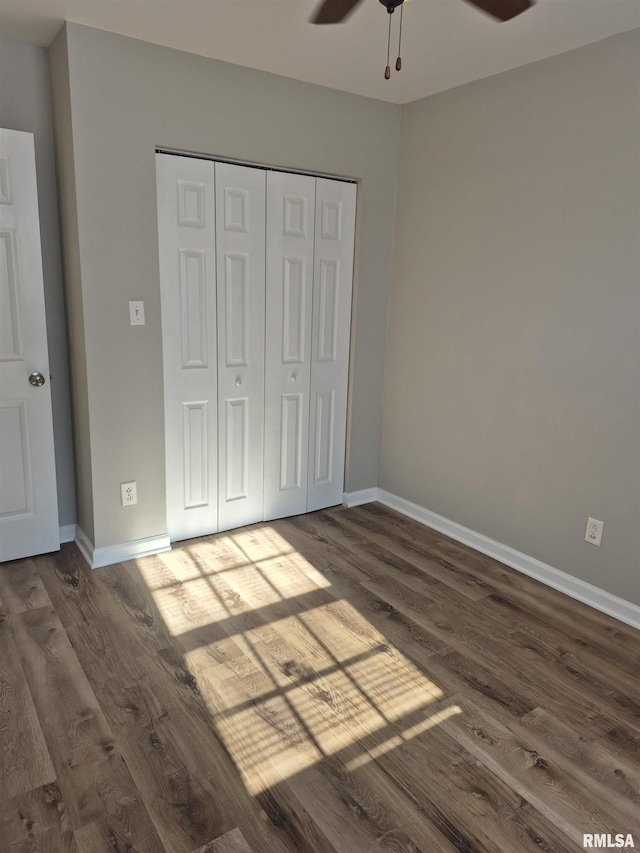 unfurnished bedroom with dark hardwood / wood-style flooring, ceiling fan, and a closet