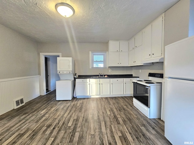 kitchen featuring sink, white cabinetry, dark hardwood / wood-style floors, white appliances, and stacked washer / dryer