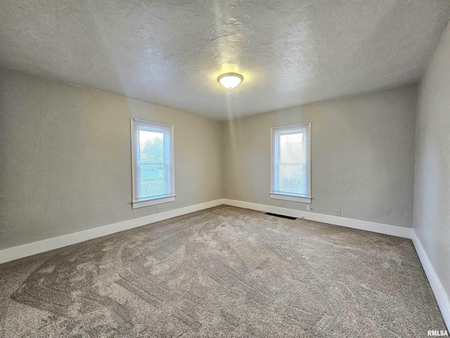 carpeted empty room featuring a textured ceiling