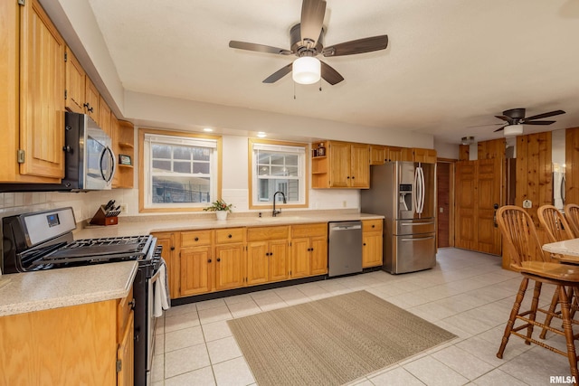 kitchen featuring appliances with stainless steel finishes, sink, decorative backsplash, light tile patterned floors, and ceiling fan