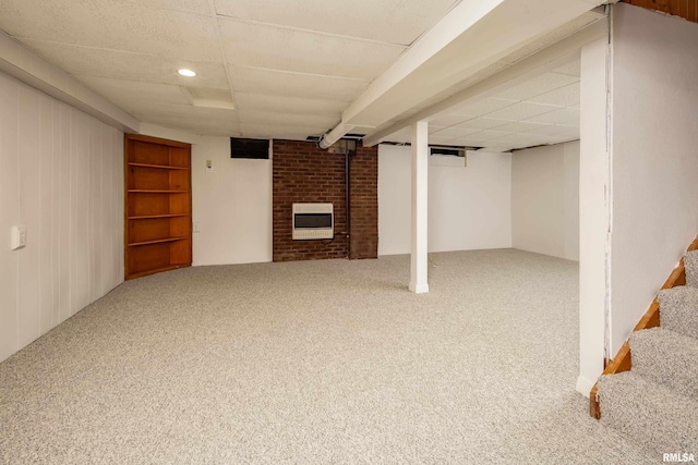 basement with heating unit, a fireplace, carpet, and a drop ceiling