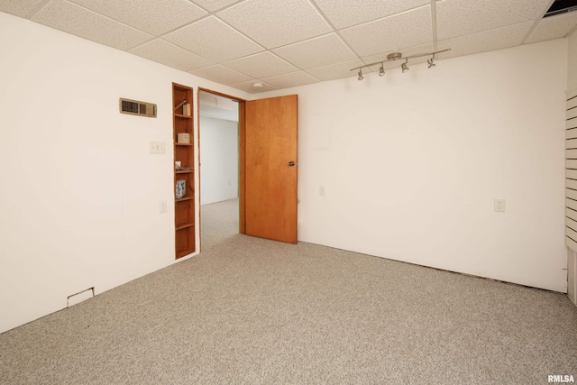 spare room featuring a drop ceiling, rail lighting, and carpet