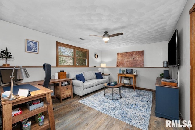 living room with dark wood-type flooring, ceiling fan, and a textured ceiling