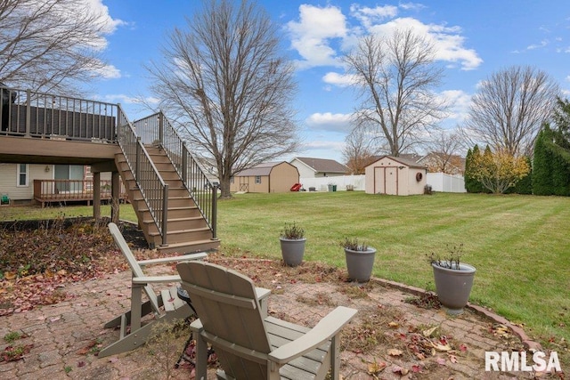 view of yard featuring a wooden deck, a patio, and a storage unit