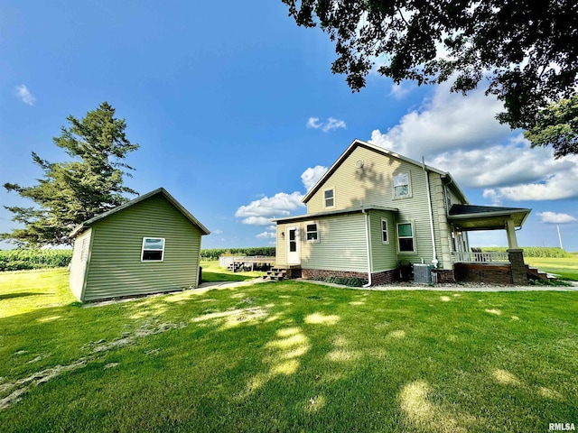 rear view of house featuring central air condition unit and a lawn