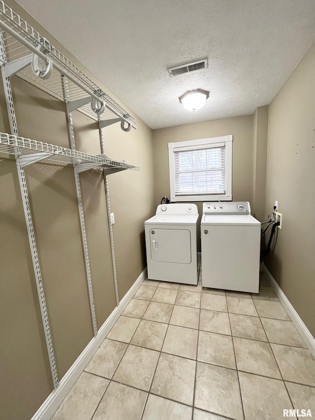 laundry area with light tile patterned flooring, washer and dryer, and a textured ceiling