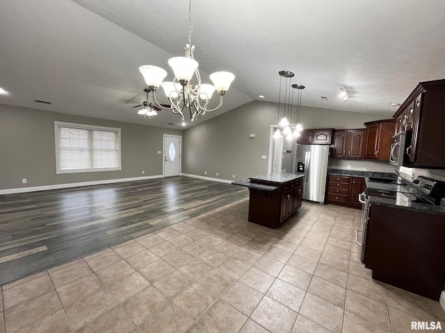 kitchen featuring dark brown cabinetry, decorative light fixtures, a center island, vaulted ceiling, and stainless steel appliances