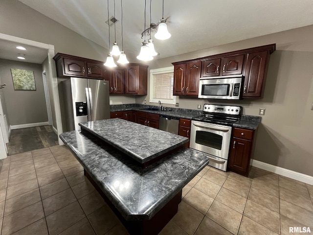 kitchen with decorative light fixtures, lofted ceiling, sink, a center island, and stainless steel appliances