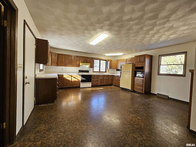 kitchen featuring fridge, electric range oven, sink, and a textured ceiling