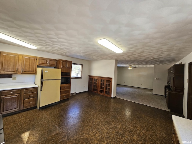 kitchen featuring ceiling fan, refrigerator, and a textured ceiling