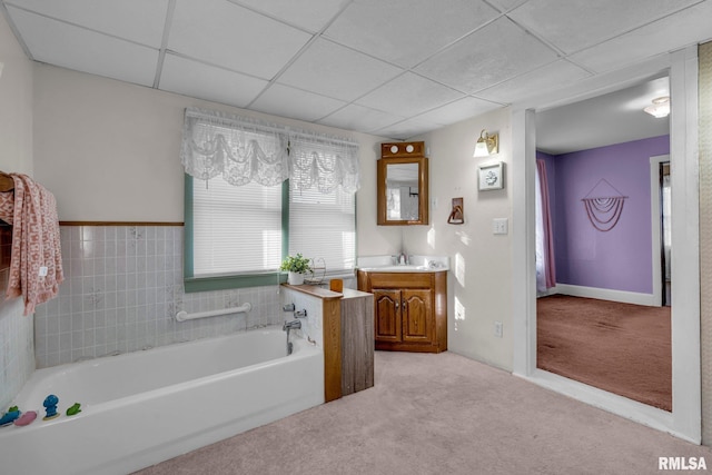 bathroom featuring vanity, a drop ceiling, and a tub to relax in