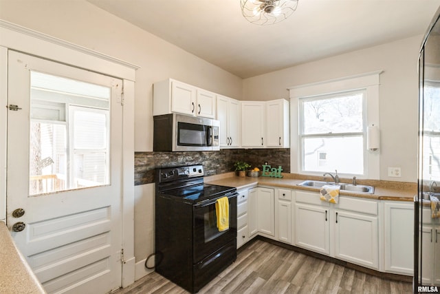 kitchen featuring tasteful backsplash, white cabinets, sink, and electric range