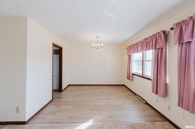 unfurnished room with a chandelier and light wood-type flooring