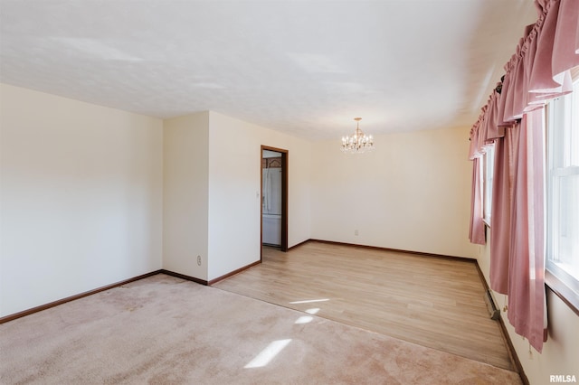 spare room with light colored carpet and a notable chandelier